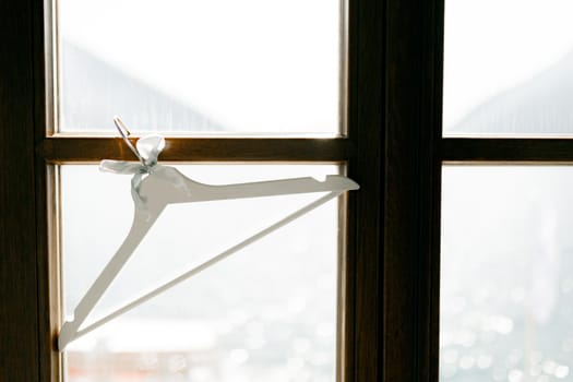 A white clothing hanger hangs on a window against the side of seawater