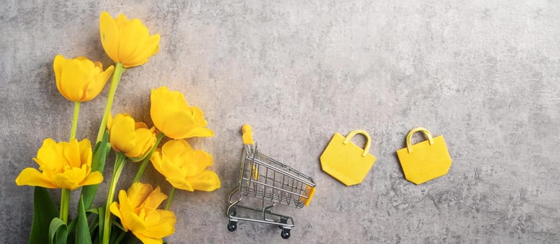 Concept of Mother's day holiday gift shopping greeting design with yellow tulip flower bouquet on gray background
