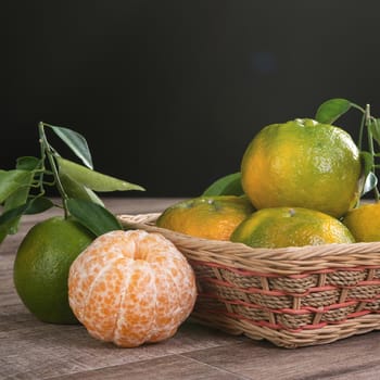 Fresh green tangerine mandarin orange with fresh leaves on dark wooden table background harvest concept.