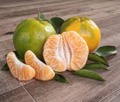 Fresh green tangerine mandarin orange with fresh leaves on dark wooden table background harvest concept.