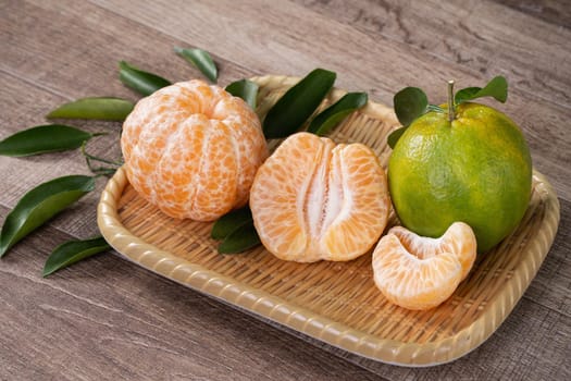 Fresh green tangerine mandarin orange with fresh leaves on dark wooden table background harvest concept.
