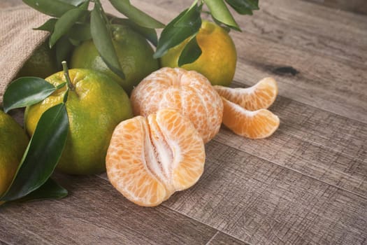 Fresh green tangerine mandarin orange with fresh leaves on dark wooden table background harvest concept.
