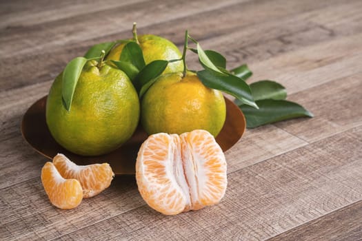 Fresh green tangerine mandarin orange with fresh leaves on dark wooden table background harvest concept.