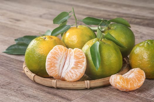 Fresh green tangerine mandarin orange with fresh leaves on dark wooden table background harvest concept.