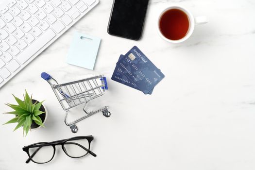 Top view of online shopping concept with credit card, smart phone and computer isolated on office marble white table background.