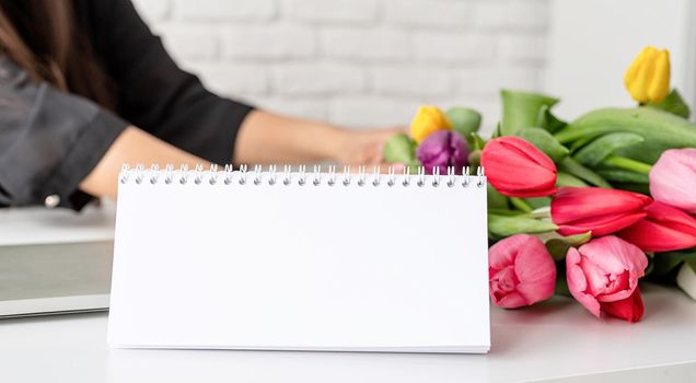 Small business concept. Spring holidays. Mock up of desk calendar with colorful tulips