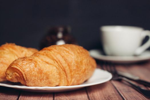 croissants white plates on the table kitchenware a cup of coffee meal dessert. High quality photo