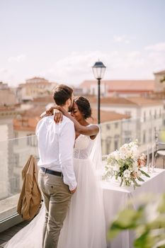Interracial wedding couple. Destination fine-art wedding in Florence, Italy. African-American bride and Caucasian groom stand near the table for wedding dinner