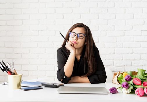 Small business concept. Portrait of young confident business woman working with flowers at the office, thinking with closed eyes