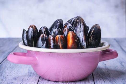 Mussels with parsley in a bowl on a wooden board. Seafood. Dark background