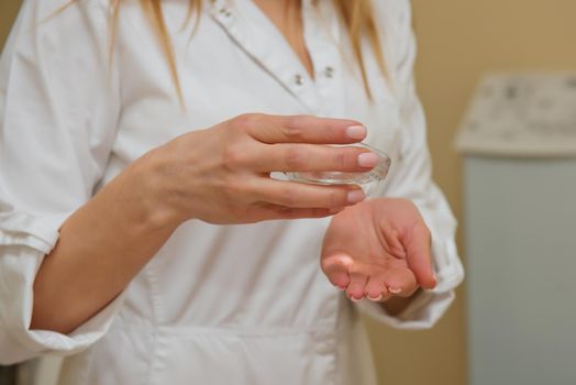 Beautician pours massage oil into his hand. Close-up.