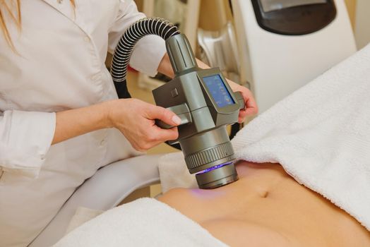 Close-up of cosmetologist doing massage with special vacuum apparatus on female belly.