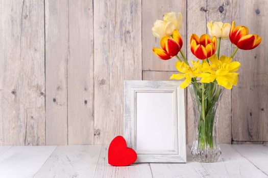Tulip flower in glass vase over wooden table background wall for Mother's Day design concept.