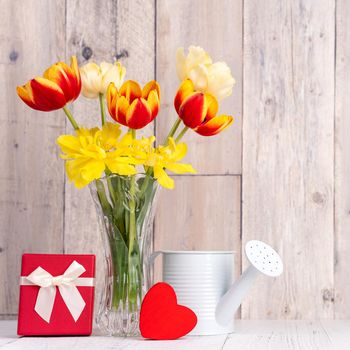 Tulip flower in glass vase over wooden table background wall for Mother's Day design concept.