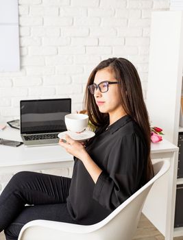 Small business concept. Portrait of young confident brunette business woman working at the office drinking tea or coffee