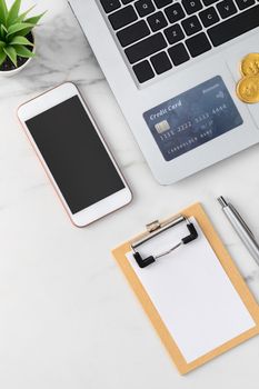 Top view of financial plan concept with credit card, laptop, note on white office table background.