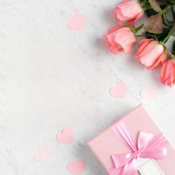 Giftbox and pink rose flower on marble white table background for Mother's Day holiday greeting design concept.