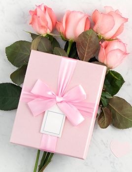 Giftbox and pink rose flower on marble white table background for Mother's Day holiday greeting design concept.