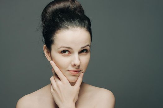 pretty brunette with bare shoulders gathered hair hand near face. High quality photo