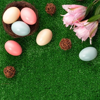 Colorful Easter eggs in the nest with pink lily flower on a lawn grass background.