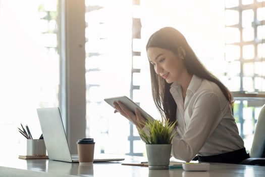 Beautiful business woman uses tablet and laptop while working in the office