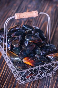 Fresh Mussels in a Basket on a wooden board. Seafood. Dark background