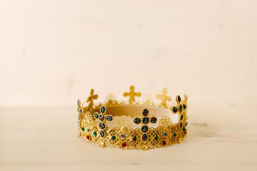 Golden crown encrusted with precious stones and crosses against a white background
