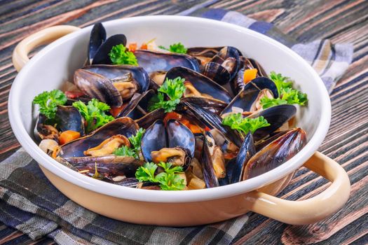 Boiled mussels in cooking dish with parsley on dark wooden background