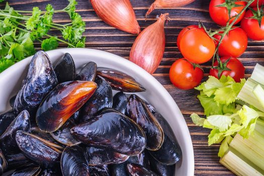 Mussels with parsley in a bowl on a wooden board. Seafood. Dark background