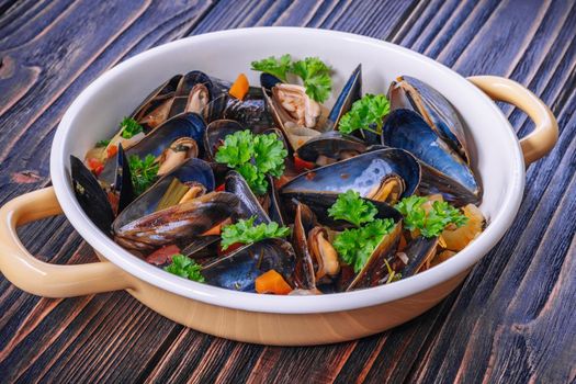 Boiled mussels in cooking dish with parsley on dark wooden background