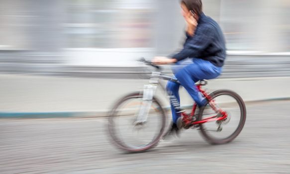 cyclist with a mobile phone on the city roadway. Intentional motion blur