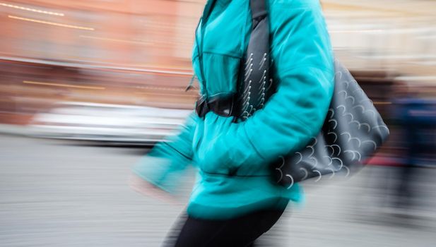 Young woman at rush hour walking in the street. Intentional motion blur
