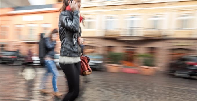 Abstract image of a young woman talking on a mobile phone on a city background. Intentional motion blur
