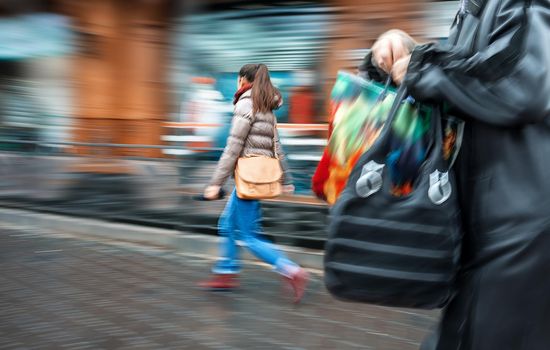 People at rush hour walking in the street.  Intentional motion blur
