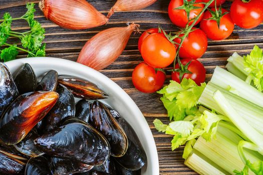 Mussels with parsley in a bowl on a wooden board. Seafood. Dark background