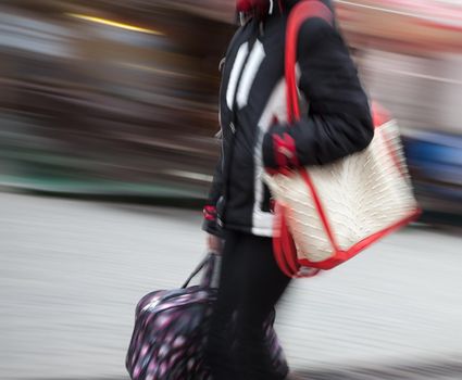 Young woman at rush hour walking in the street. Intentional motion blur
