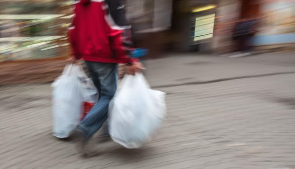 Abstract image of a man in sportswear with shopping plastic bags. Intentional motion blur