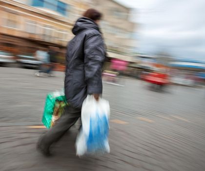 Abstract image of a woman in a jacket with shopping plastic bags. 
