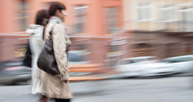Two young woman at rush hour walking in the street. Intentional motion blur