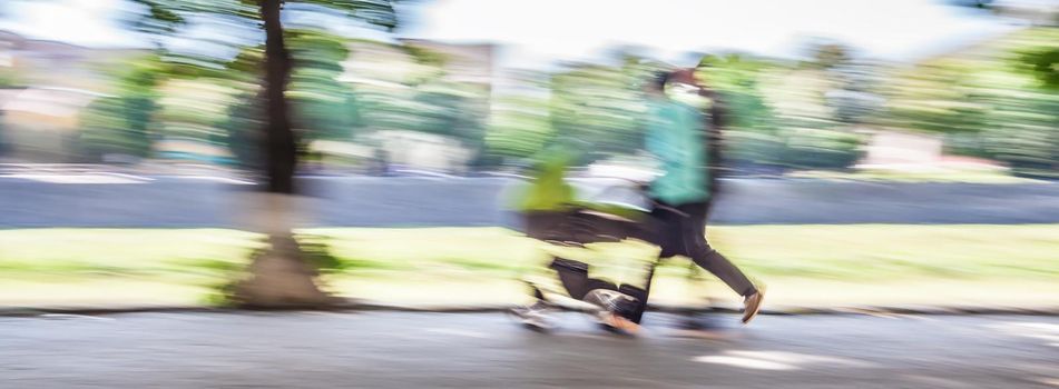 Young family with small children and a pram walking down the street. Intentional motion blur