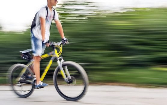 Boy cyclist in traffic on the city roadway. Intentional motion blur