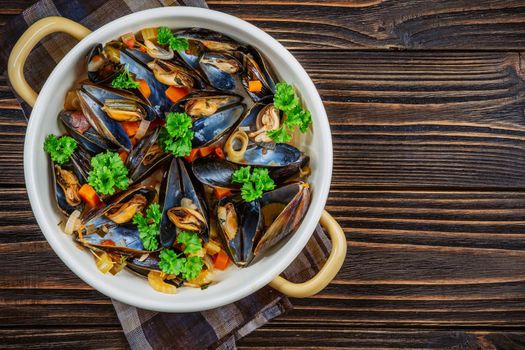 Boiled mussels in cooking dish with parsley on dark wooden background