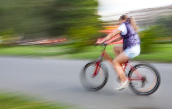 Girl cyclist in traffic on the city roadway. Intentional motion blur