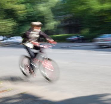 Boy cyclist in traffic on the city roadway. Intentional motion blur