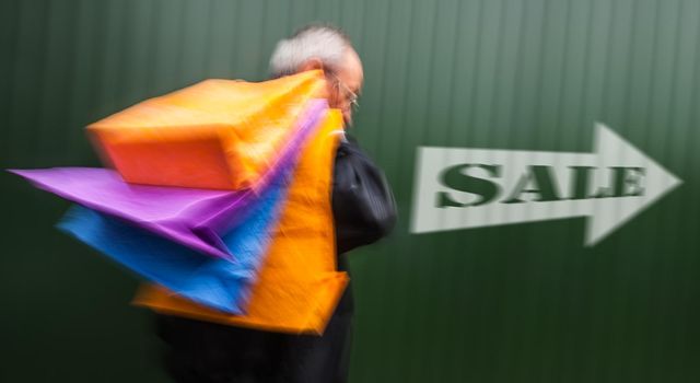 Holiday sales. An elderly man with many shopping bags in his hand. Intentional motion blur