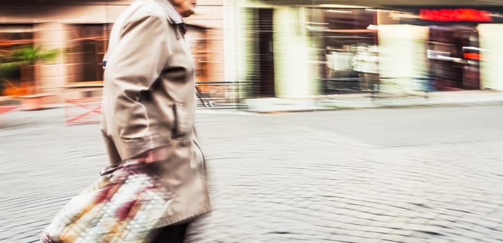 Abstract blurred image of an old woman in the city. Intentional motion blur