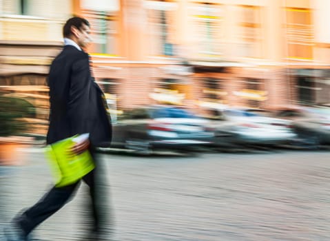 Businessman with documents in a folder for papers in a suit walks down the street. Intentional motion blur image