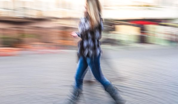 Soft focus blurred abstract image of young woman in the street. Intentional motion blur
