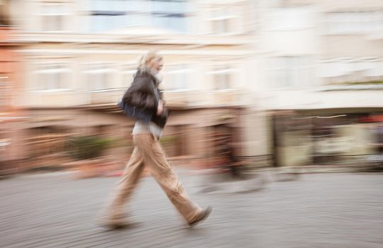 Soft focus blurred abstract image of young woman in the street. Intentional motion blur