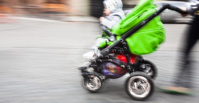 Mother with small children and a pram walking down the street. Intentional motion blur